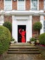 Deborah staat in de deuropening van haar woning in het Londense Holland Park met een felrode krans op de voordeur. Fotografie: Ingrid Rasmussen / Living Inside