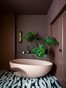 In de badkamer wordt een roze badkuip van Sanitairwinkel.nl gecombineerd met houtwerk in een warme aubergine-tint. Fotografie: Eddy Wenting
